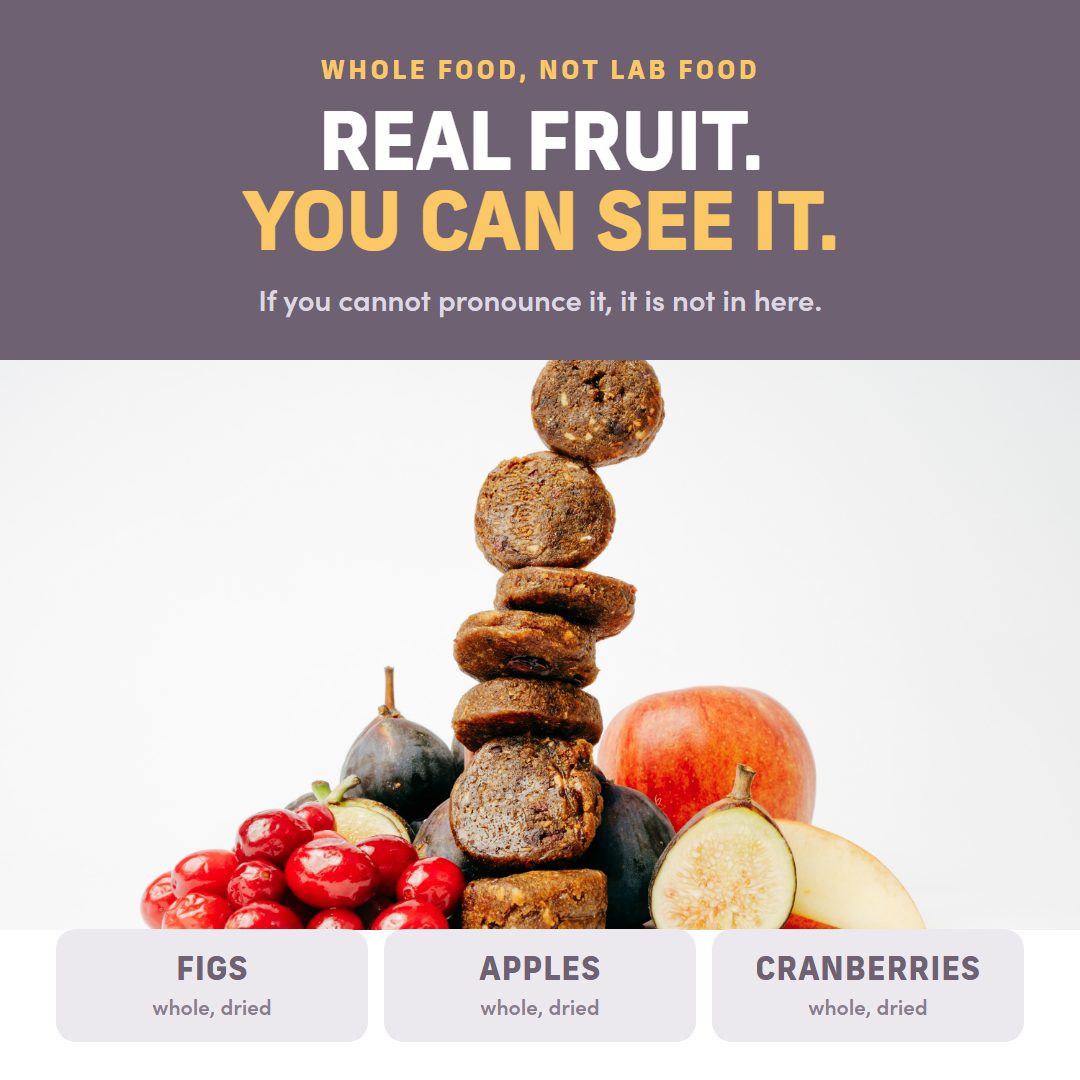 Central stack of dried figs balanced on top of dried apples and cranberries, surrounded by fresh figs, an apple, and cranberries. The top banner reads 'WHOLE FOOD, NOT LAB FOOD.